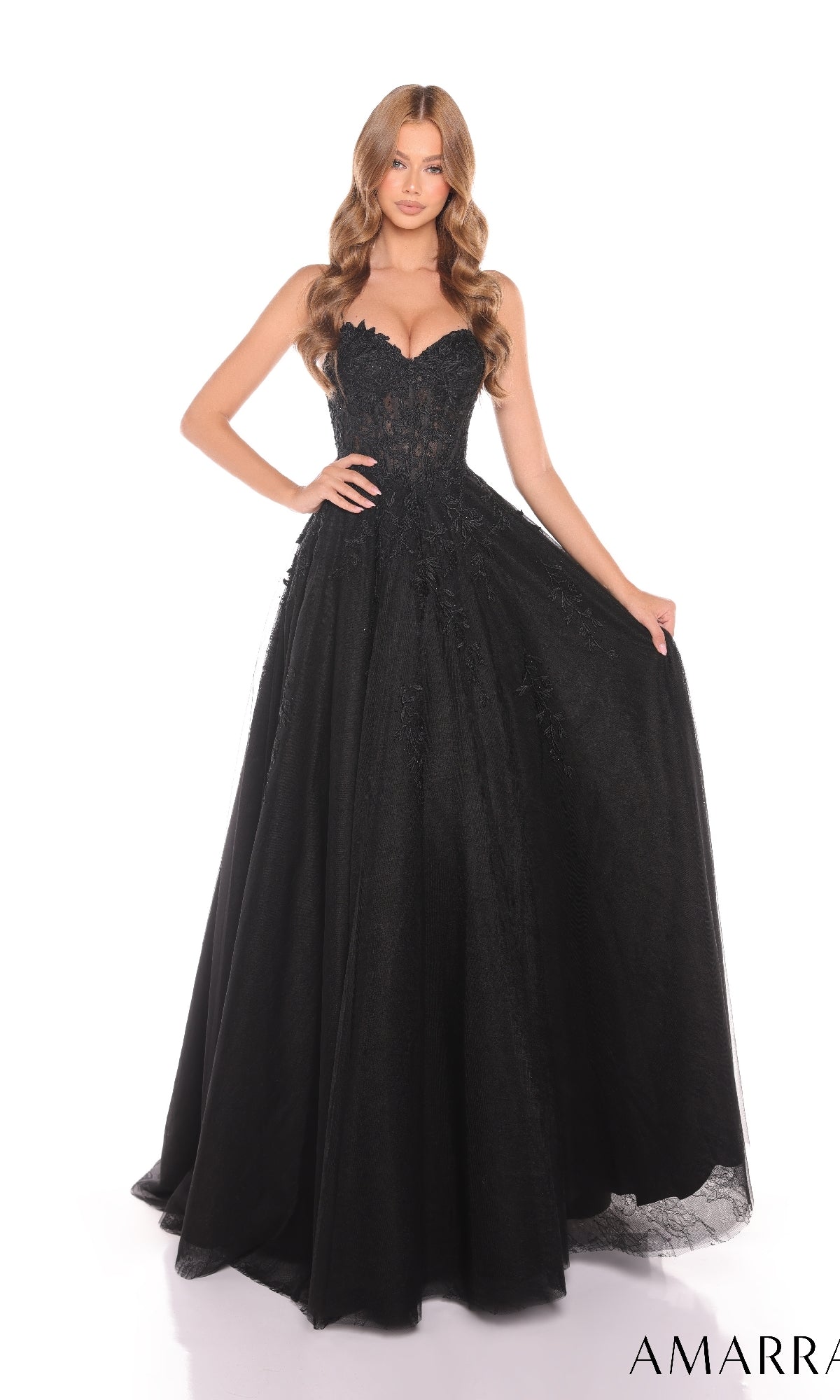 A woman stands against a white background wearing the Amarra 88413 Lace Prom Ball Gown?a strapless, floor-length black dress with a fitted corset bodice and delicate floral lace appliques.